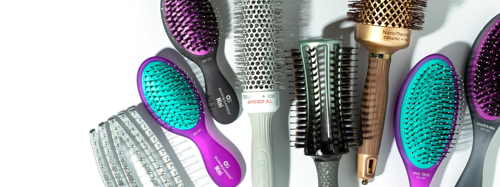 Olivia Garden hair brushes laid out in a stylish arrangement, showcasing a variety of professional-grade options including round thermal brushes, detangling brushes, and eco-friendly bamboo brushes, ideal for all hair types and styling needs.