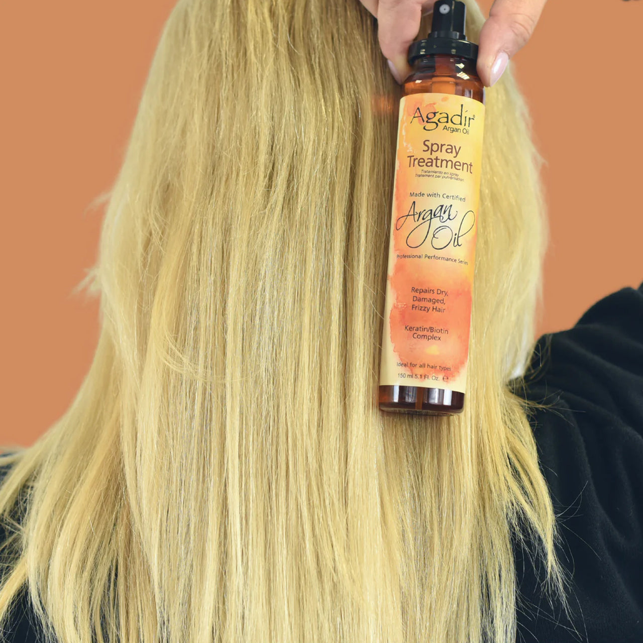 Close-up of the Agadir Argan Oil Spray Treatment being sprayed onto hair, showing its fine mist.